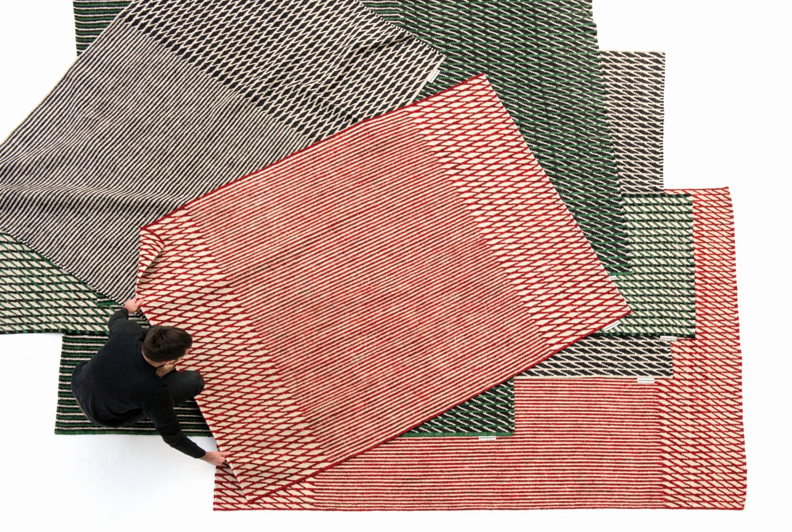 Ansicht von oben: Mehrere Nanimarquina Läufer Teppiche in Rot, Grün und Schwarz mit geometrischem Muster.