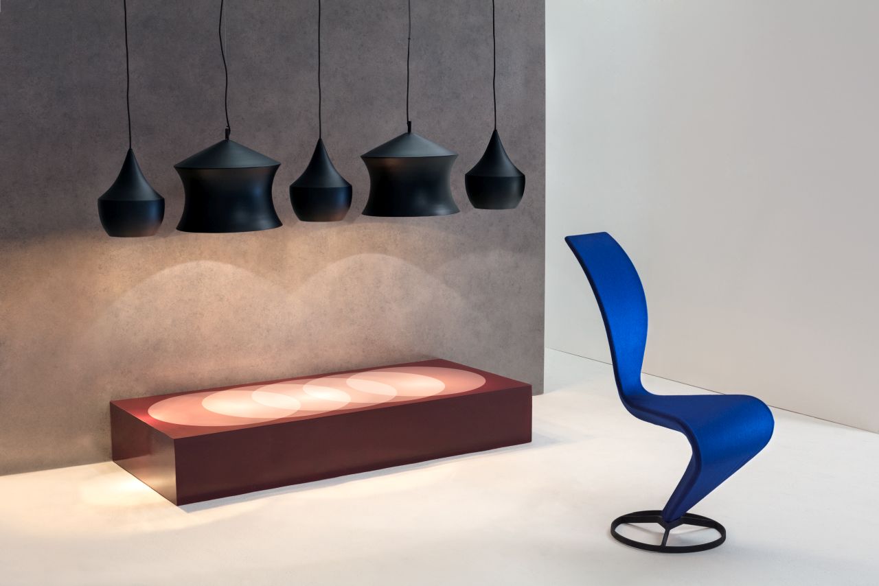 Fünf schwarze Beat Waist Pendelleuchten von Tom Dixon über einem beleuchteten Sideboard und einem blauen Stuhl.