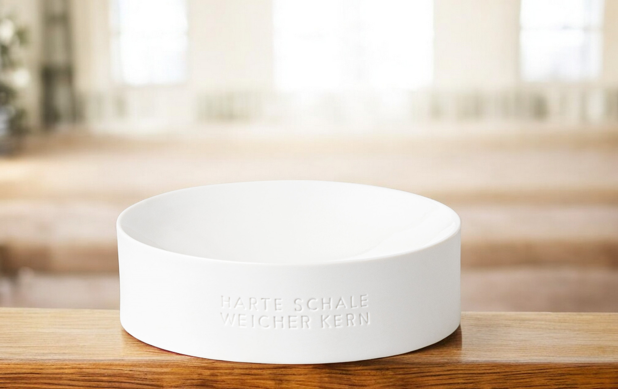 Weiße Nusschale "Harte Schale weicher Kern" von Räder auf einem Holztisch. Dekorative Schale.