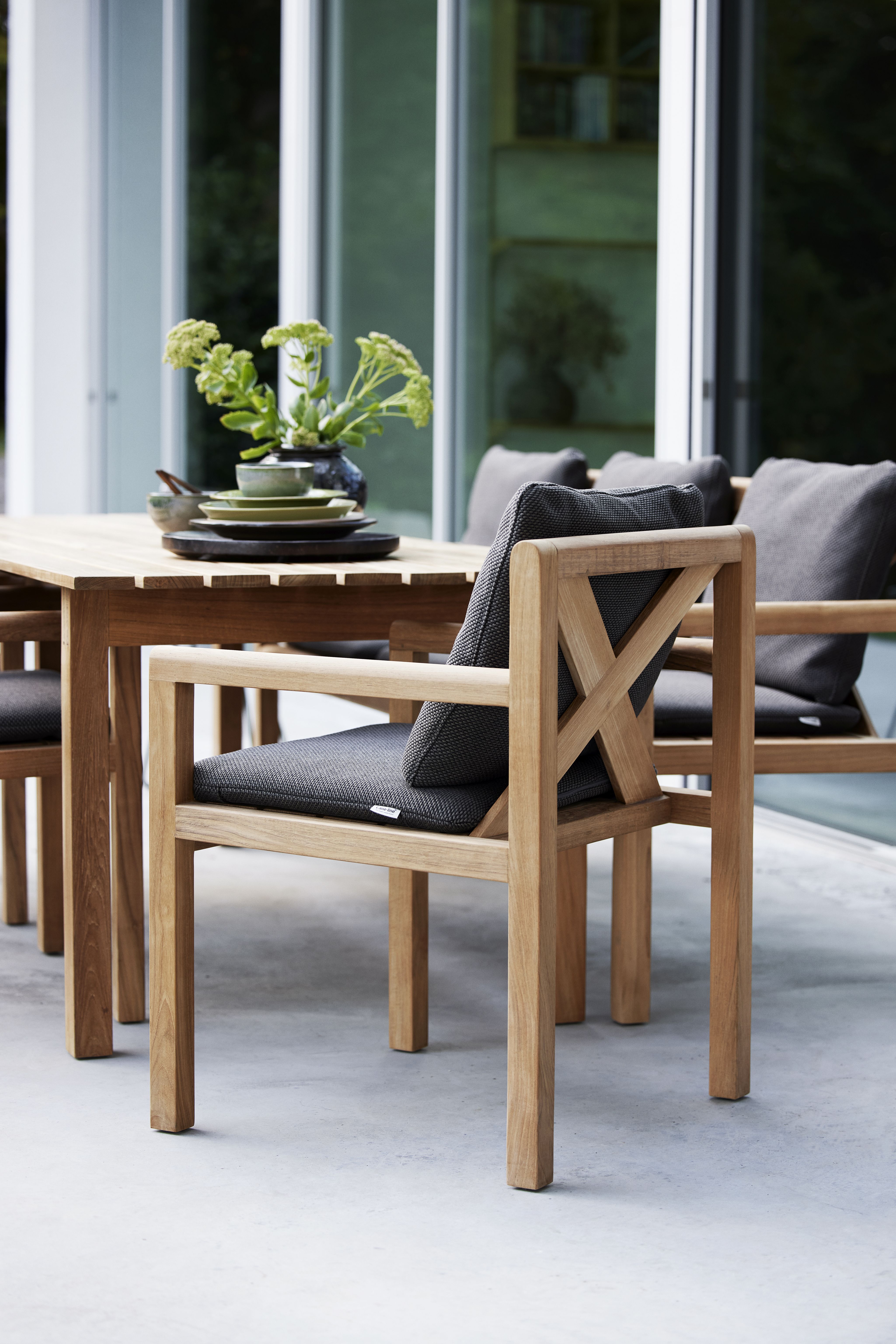 Grace Sessel von Cane-Line aus Teakholz mit grauen Kissen für den Garten.