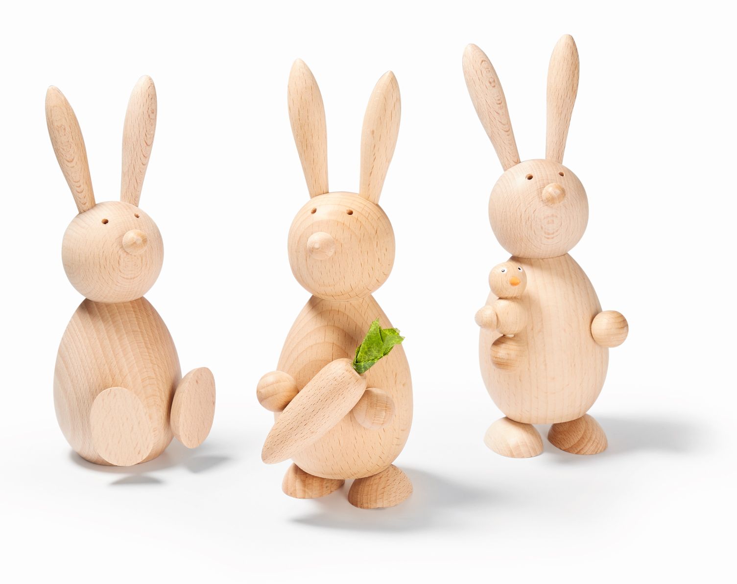 Drei hölzerne Marti Hasen, einer mit Karotte, einer mit Vogel, Osterdekoration.
