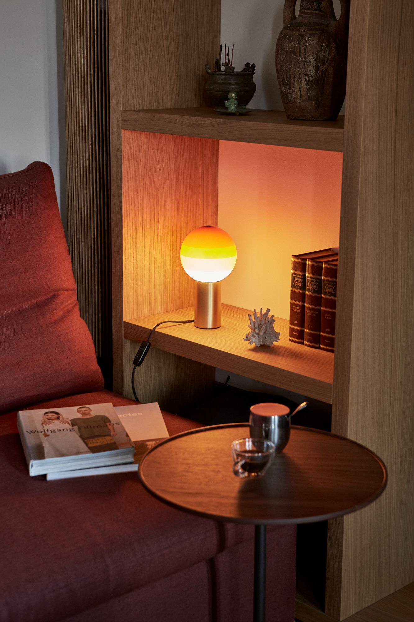 Marset Dipping Light S LED Tischleuchte mit farbigem Glasschirm und warmem Licht im Regal.