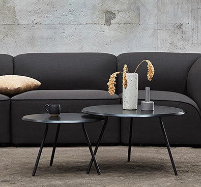 Schwarzer Soround Coffee Table Couchtisch von Woud, runder Beistelltisch aus Metall vor dunklem Sofa.