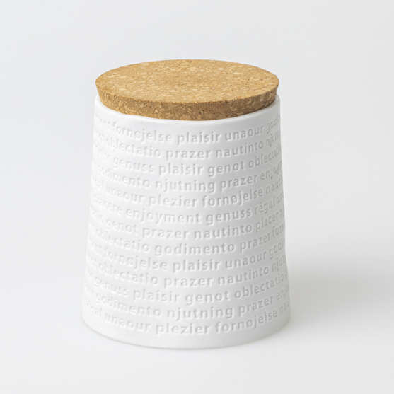 Raumpoesie Vorratsdose mit Korkdeckel: Weiße Dose mit dem Wort "Genuss" in verschiedenen Sprachen.