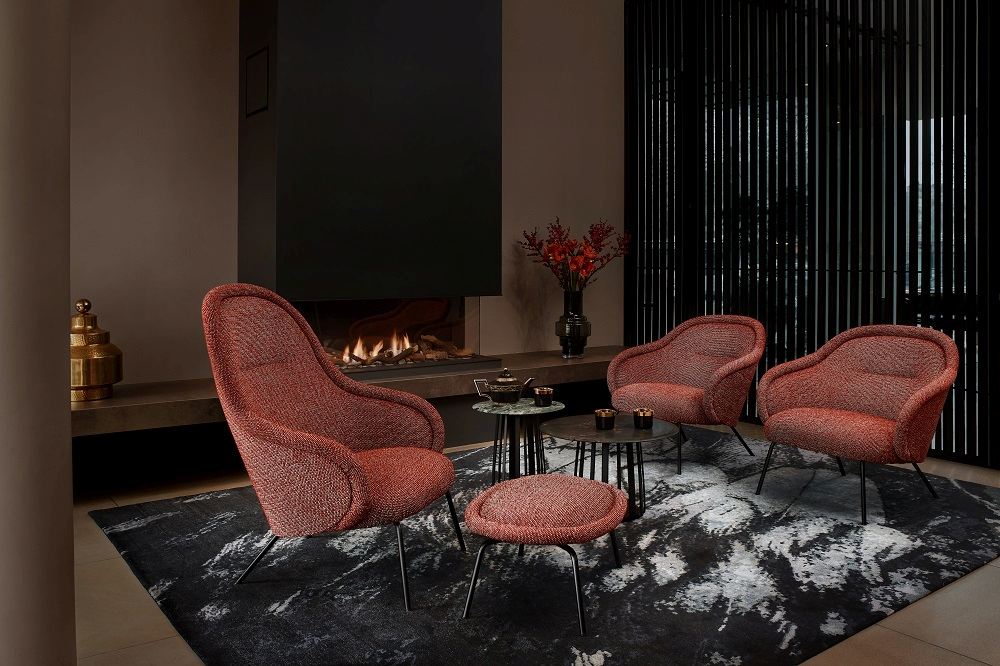 Ona Lounge Chair: Hochwertiger Sessel von Freifrau Manufaktur in Rotbraun vor Kamin. Gemütliches Wohnambiente.