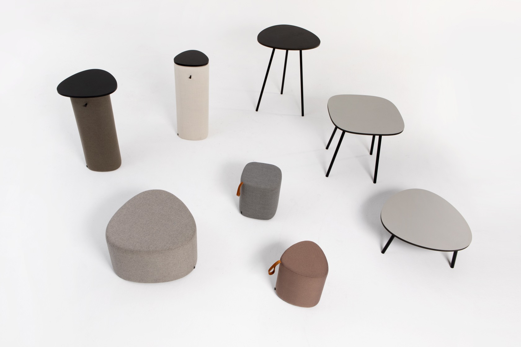 Verschiedene Cascando Hocker und Tische in Dreiecksformen und neutralen Farben auf weißem Hintergrund.