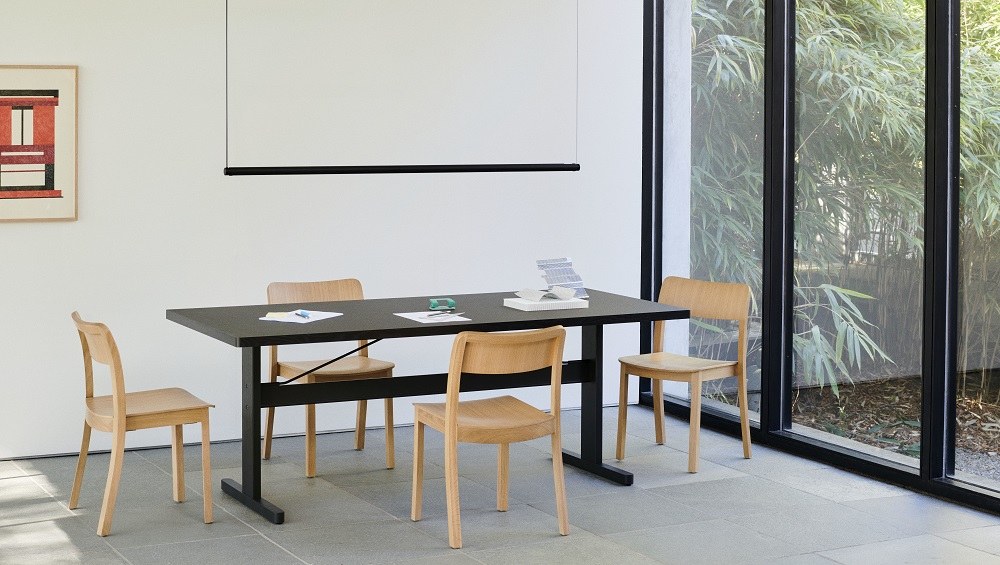 Schwarzer Hay Passerelle Tisch mit Holzstühlen in einem hellen Raum, modernes Design für Esszimmer oder Büro.
