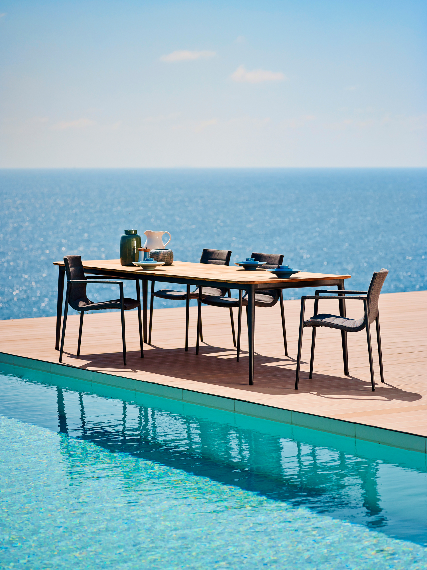 Cane-Line Core Outdoor Esstisch aus Teakholz mit Stühlen am Pool. Hochwertige Gartenmöbel.