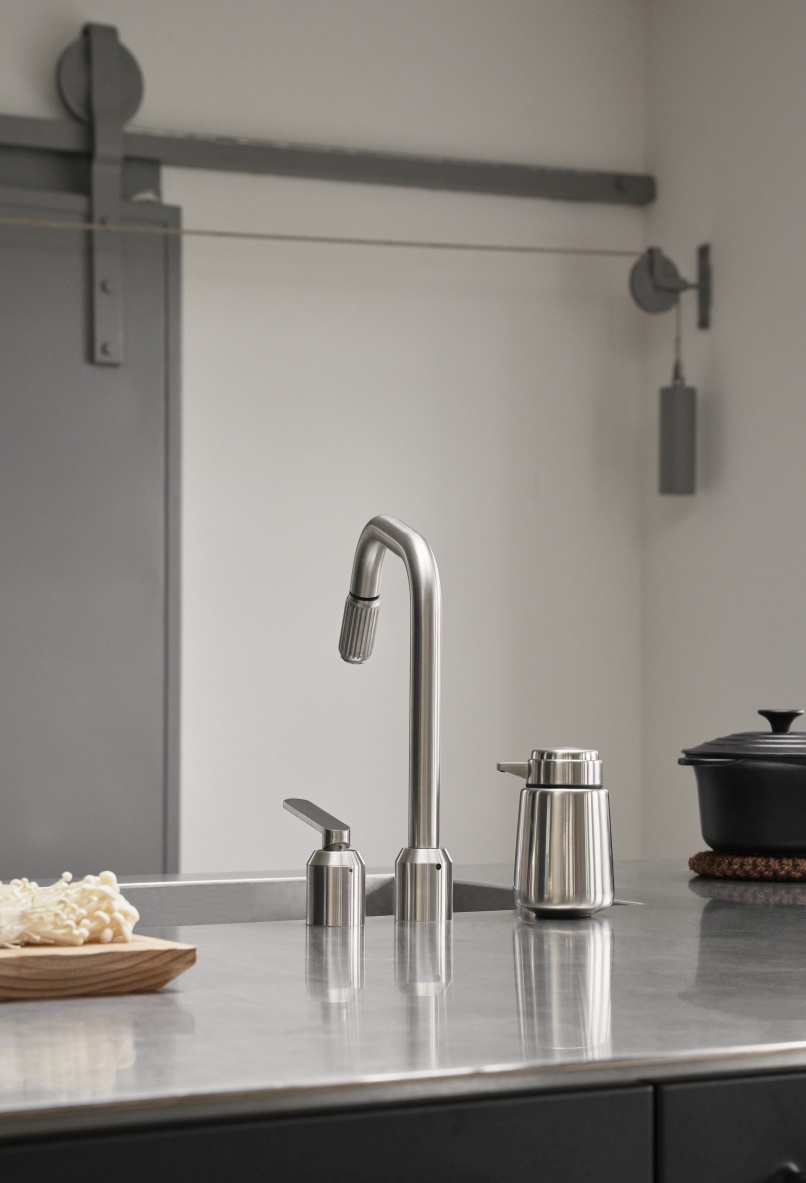 Edelstahl Seifenspender von Vipp neben einer Küchenarmatur auf einer modernen Küchenarbeitsplatte.