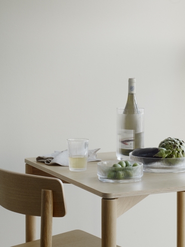 Produktfoto: Stelton Pilastro Servierschale klein mit Oliven, Glas und Weinkühler auf einem Tisch.