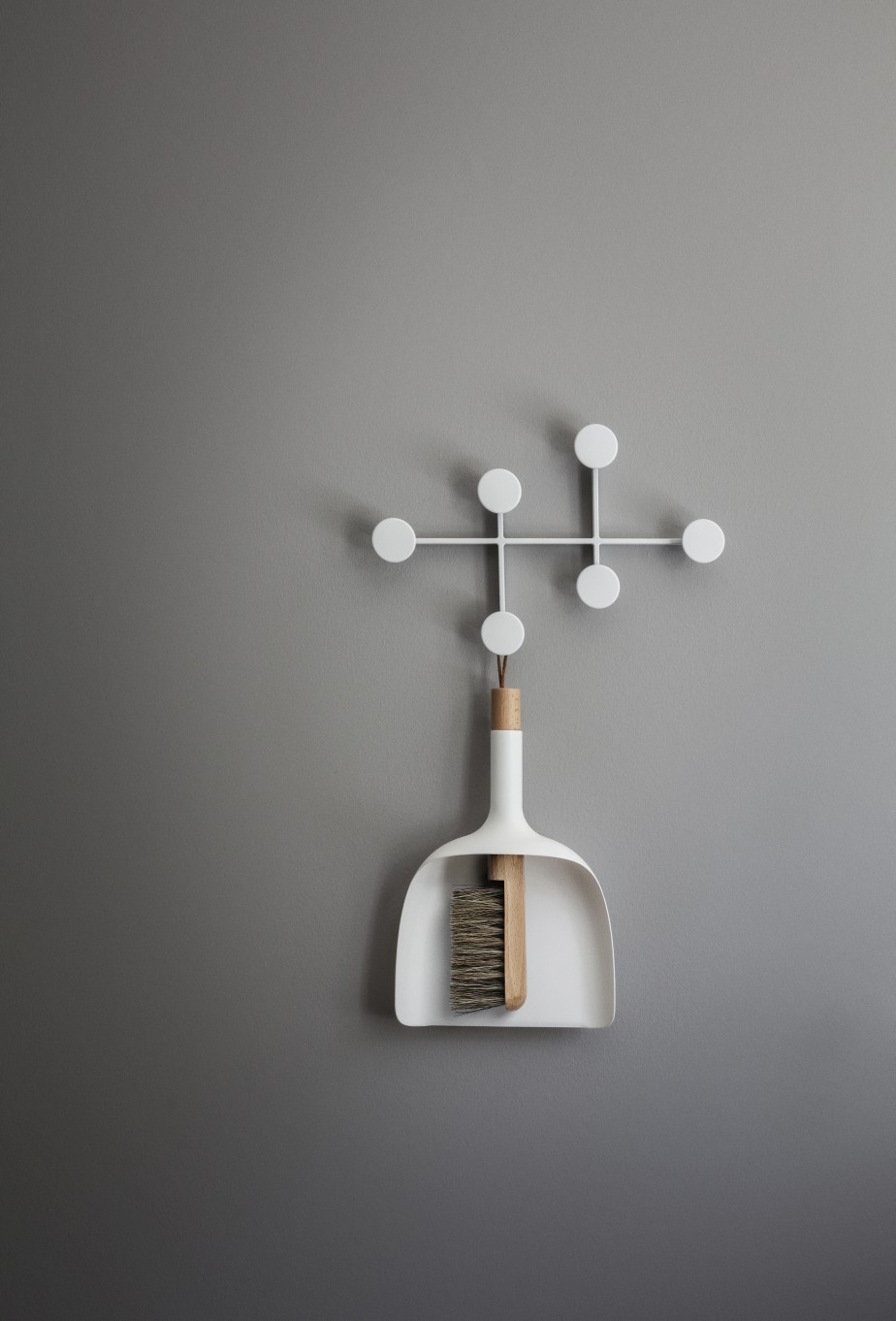 Weißer Afteroom Garderobenhaken von Audo mit Kehrschaufel und Besen an grauer Wand. Moderner Wandhaken.