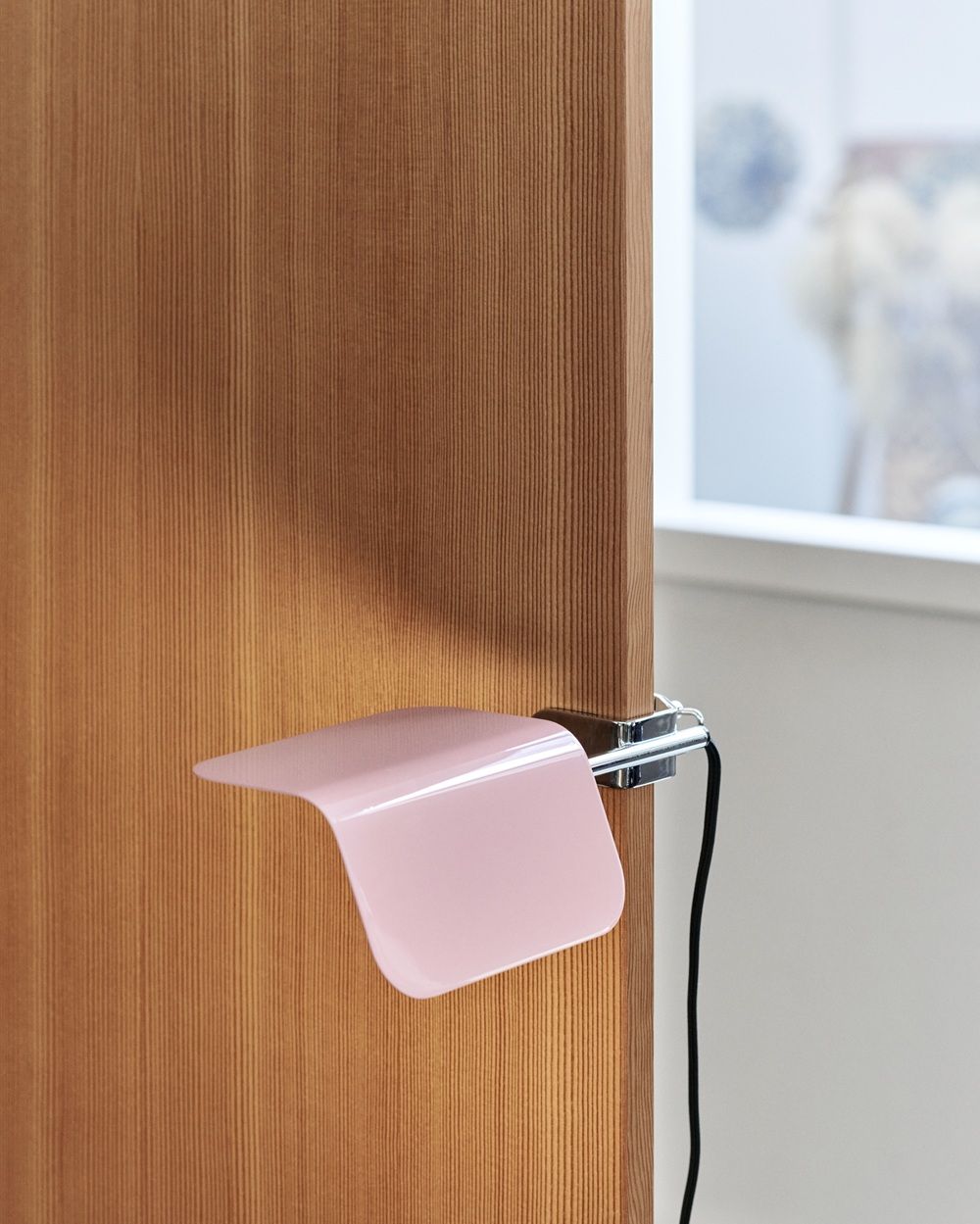 Nahaufnahme der roten Hay Apex Clip Lamp Klemmleuchte, befestigt an einem Holzregal mit Büchern.