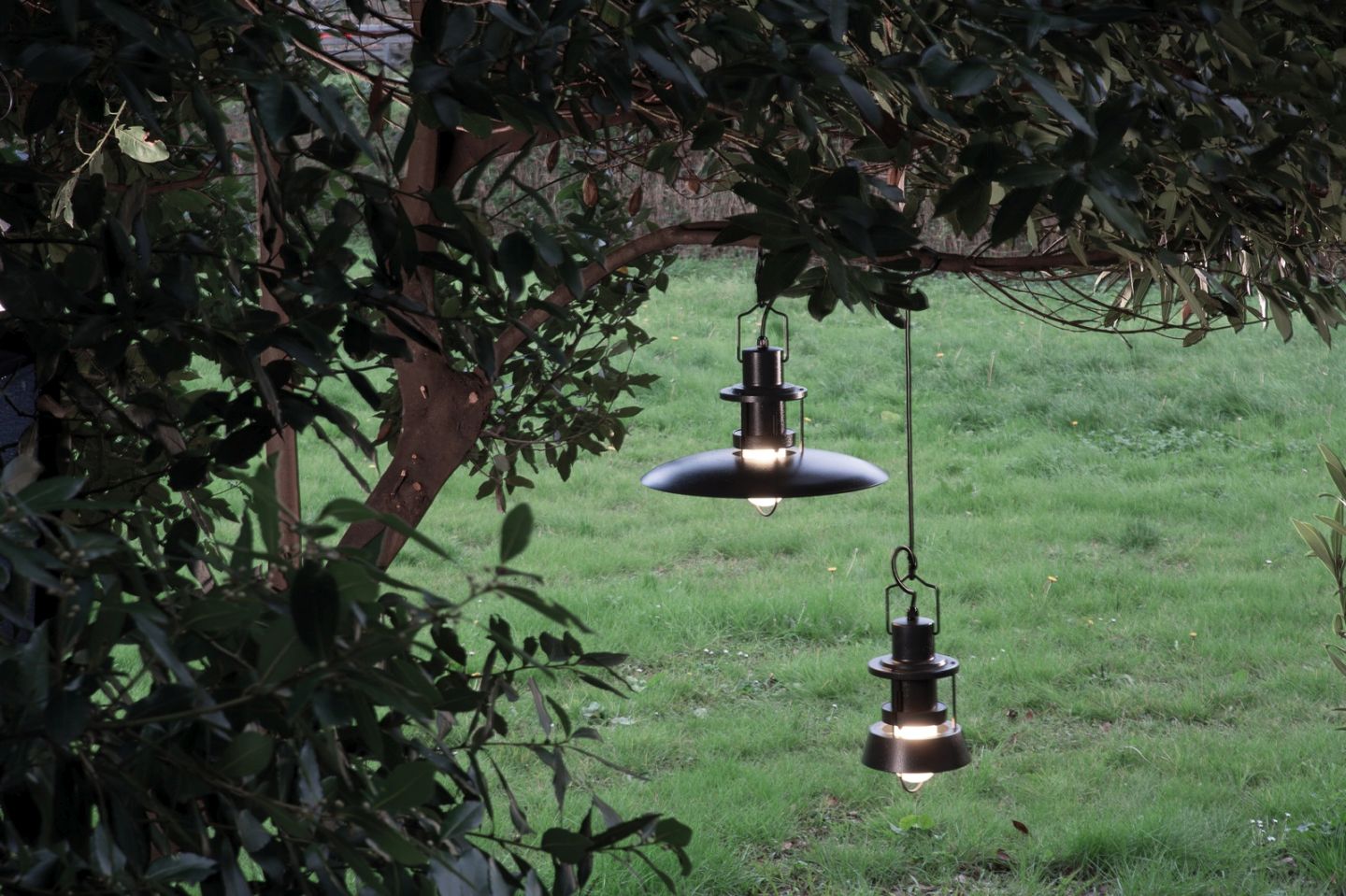 Martinelli Luce Polo Outdoor Pendelleuchte, zwei schwarze Hängelampen im Garten an einem Baum.