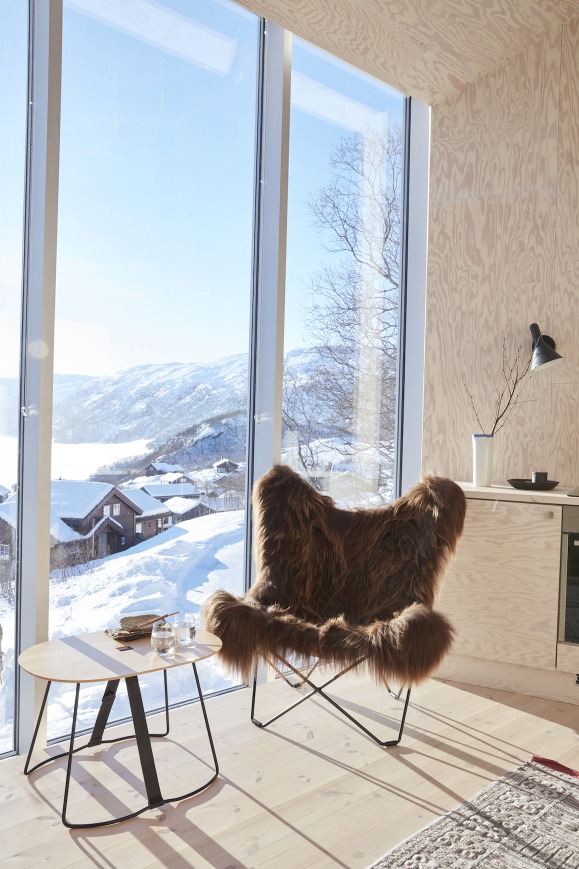 Iceland Mariposa Sessel mit Schaffell in Cuero Braun vor winterlicher Landschaft. Design Möbel.