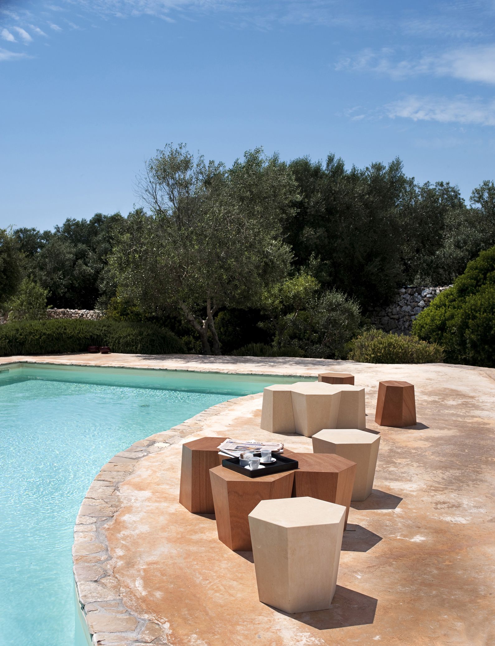 Weißer Hexagon Hocker von Casamania Horm neben Pool. Moderner Design Hocker für Garten und Terrasse.