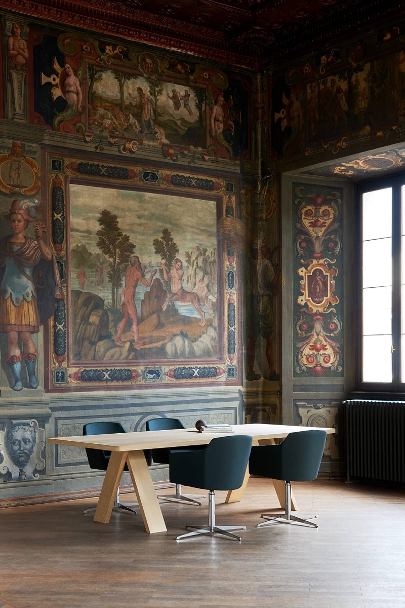 Artful Wood Table Holztisch von Segis mit hellen Holzbeinen und Stühlen in historischem Raum.