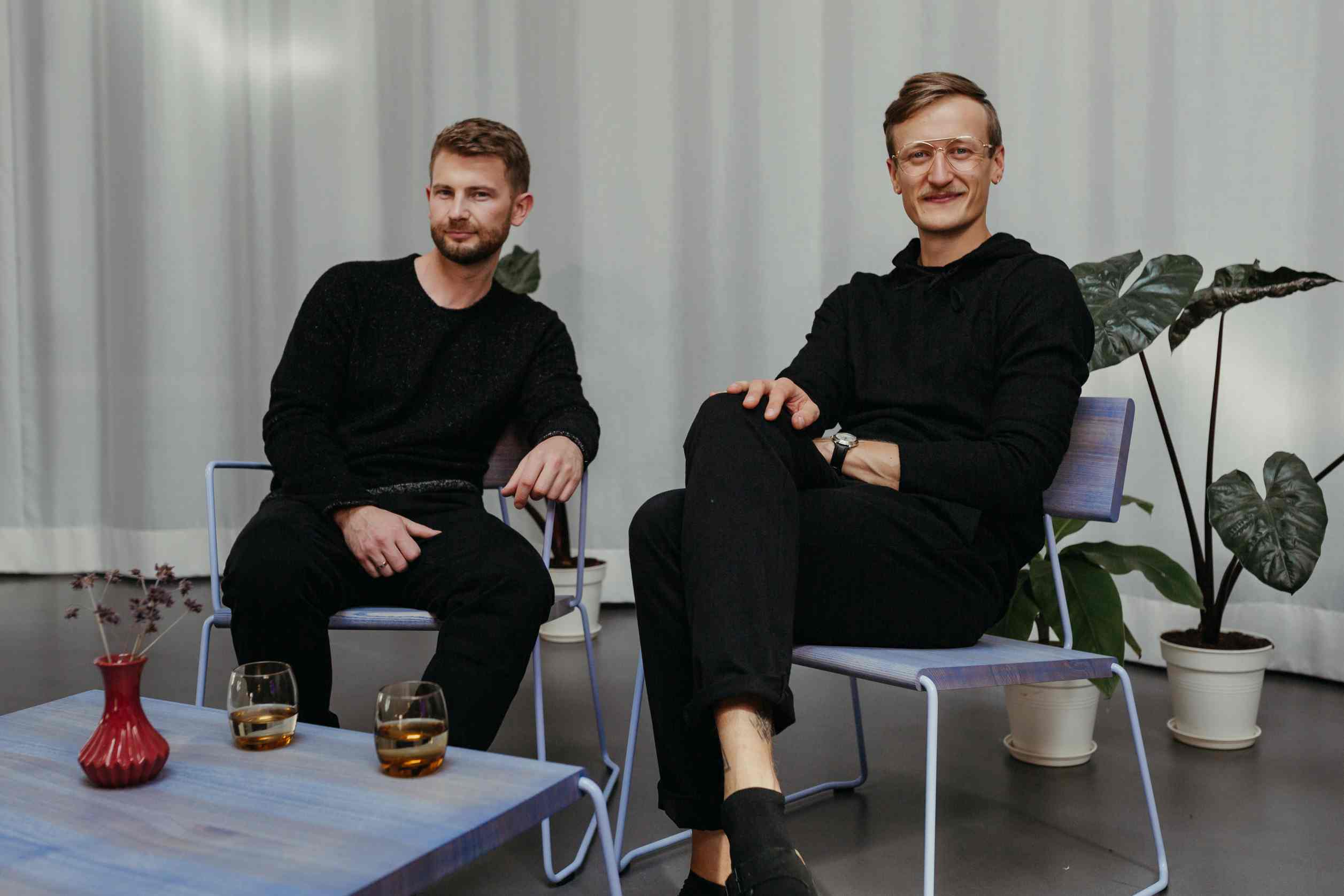 D:009 Coffeetable Fuchs & Habicht: Moderner Couchtisch aus Holz mit zwei Männern und Getränken.