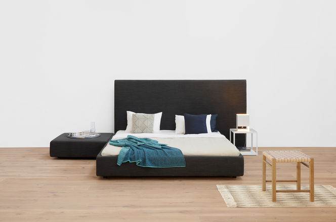 Schlafzimmer-Szene mit e15 LT02 Seam Two Tischleuchte auf einem Nachttisch neben einem Bett.