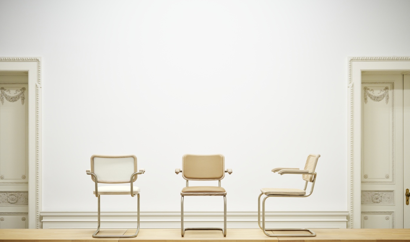 Drei JS. Thonet Freischwinger S 64 V Stühle in Beige, Weiß und Rattan vor weißer Wand.