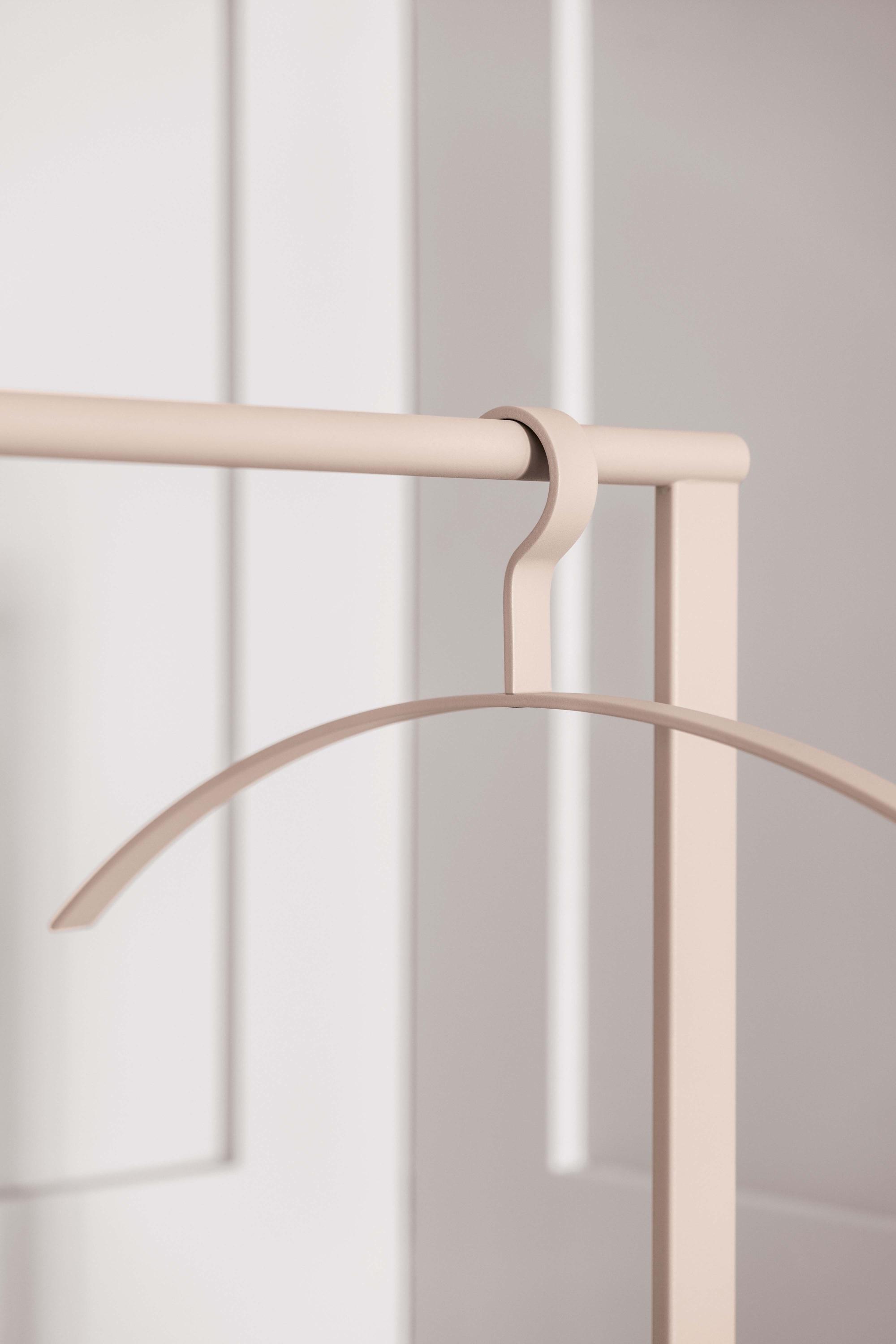 Beiger Schönbuch Garderobenständer mit Kleiderbügel vor weißer Wand, minimalistisches Design.