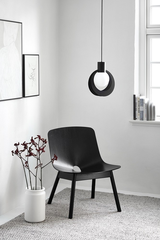 Schwarze Lunar Pendelleuchte von Woud über einem Stuhl in einem minimalistischen Raum. Design Lampe.