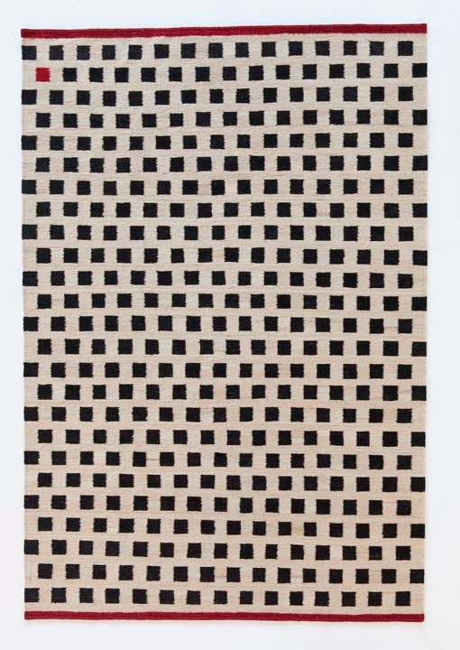 Nanimarquina Teppich mit Muster aus schwarzen Quadraten auf beigem Grund und rotem Rand.