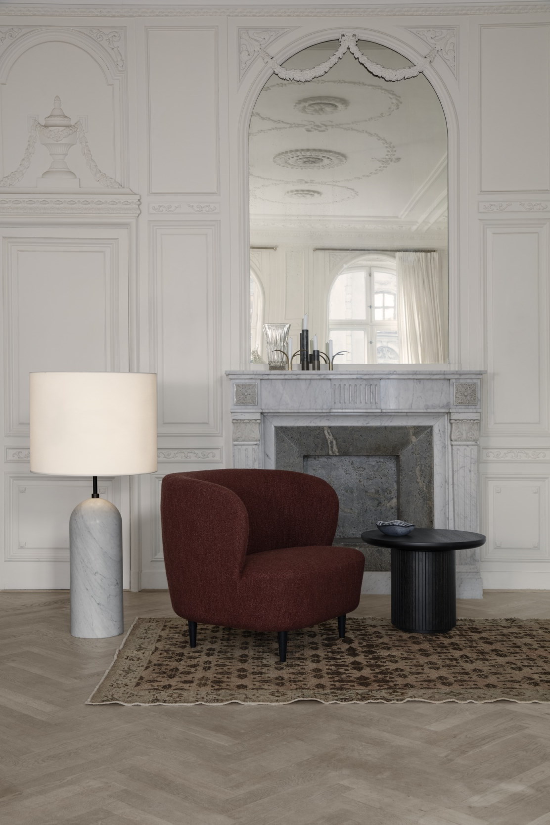 Schwarzer Gubi Moon Couchtisch 60 neben rotem Sessel auf gemustertem Teppich in stilvollem Wohnzimmer.