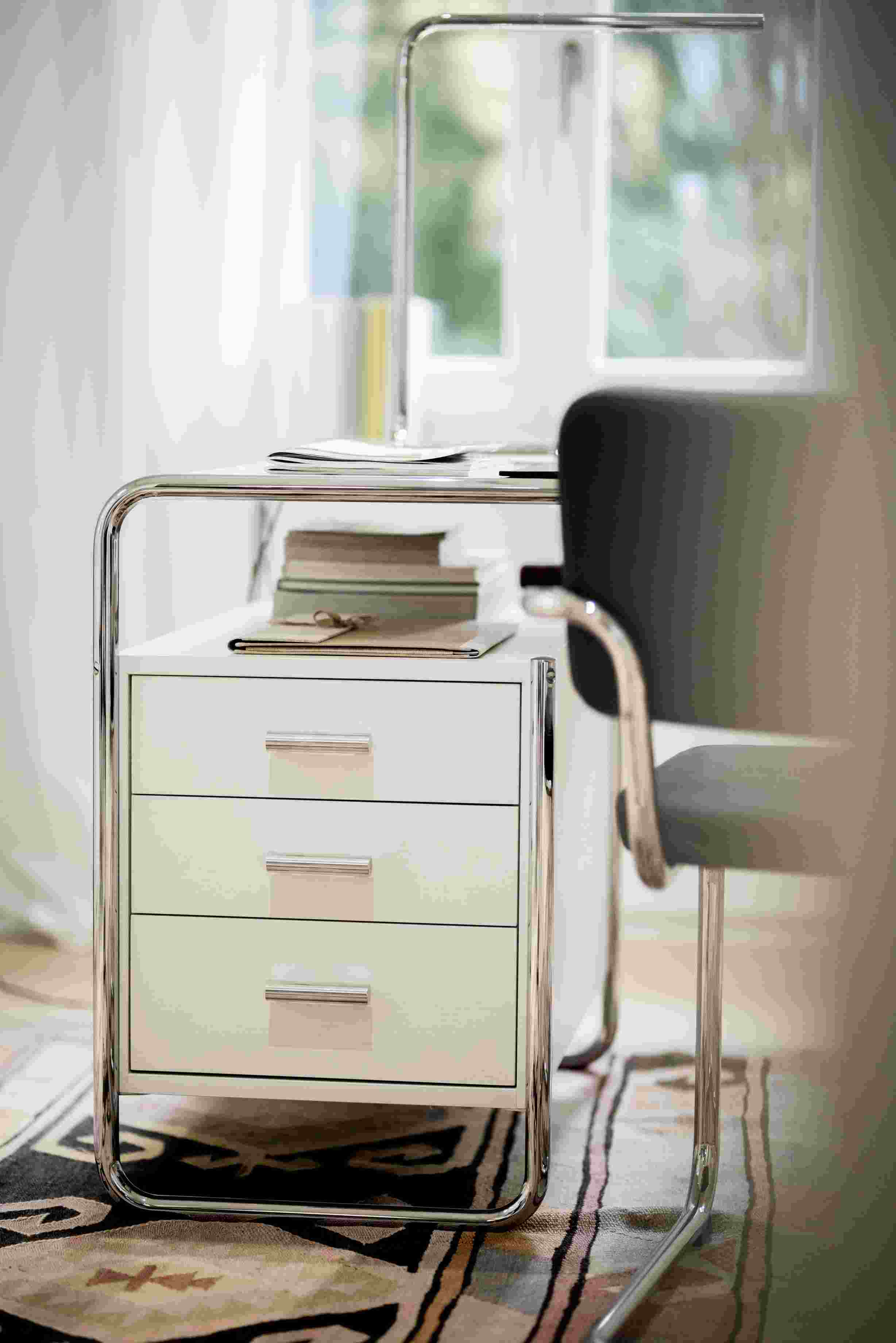 Lum 50 Tischleuchte von Thonet, verchromt, mit drei Schubladen und Büchern auf dem Schreibtisch.