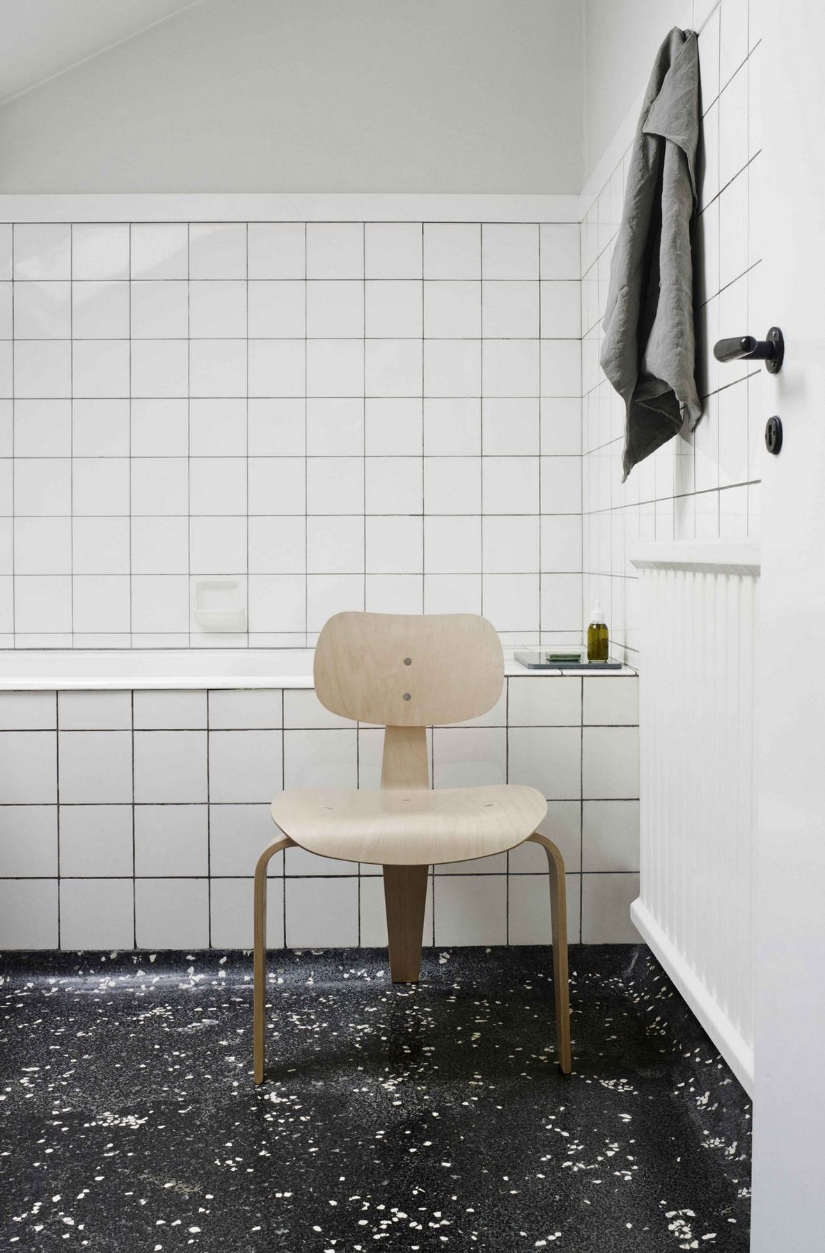 SE 42 Stuhl von Wilde+Spieth im Badezimmer mit weißen Fliesen und dunklem Terrazzoboden.