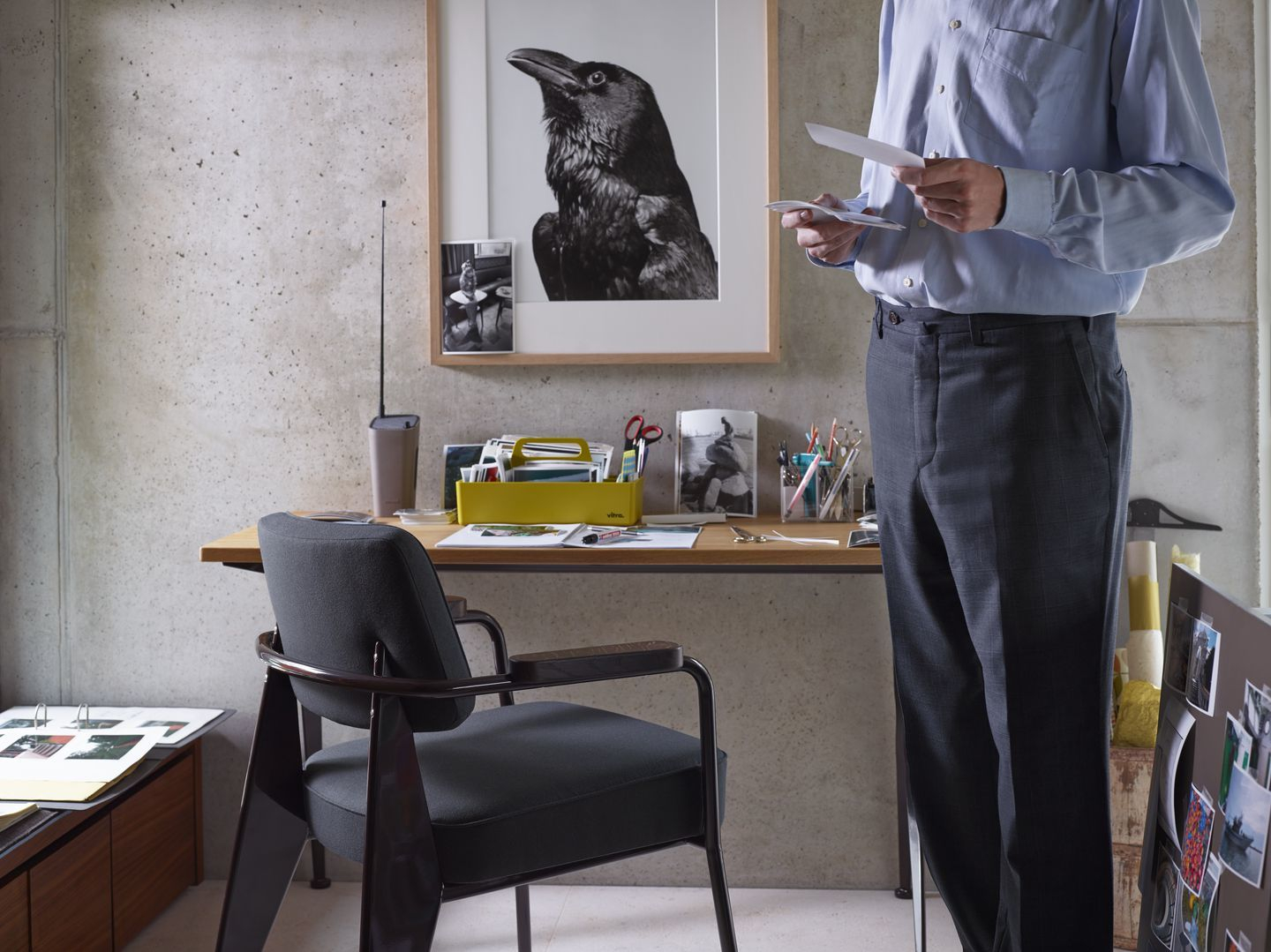 Vitra Fauteuil Direction Sessel in Grau vor einem Schreibtisch mit Büroaccessoires.