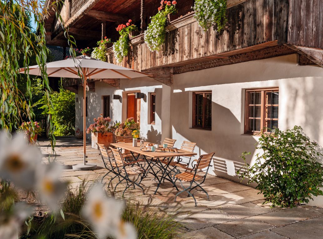 Weishäupl Classic Tisch, 120 cm, dunkelgrün, im Außenbereich mit Stühlen und Sonnenschirm.