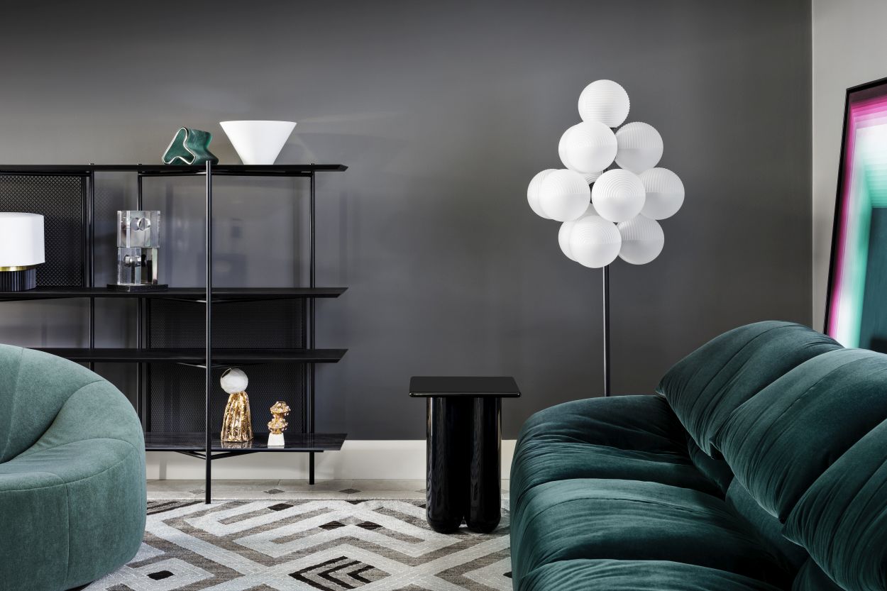 Stilvolles Wohnzimmer mit Stellar Grape Stehleuchte von Pulpo, transparent-schwarz, neben grünem Sofa.