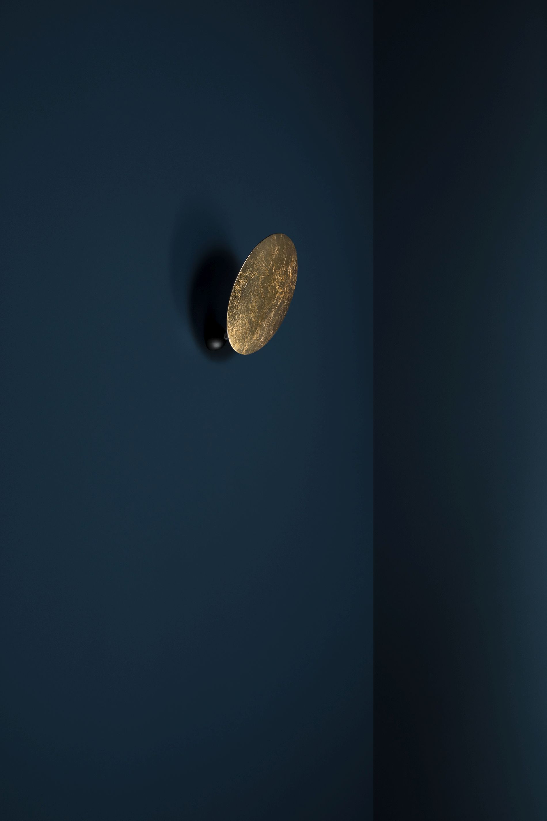 Goldene Lederam Wandleuchte von Catellani & Smith an blauer Wand, modernes Design.