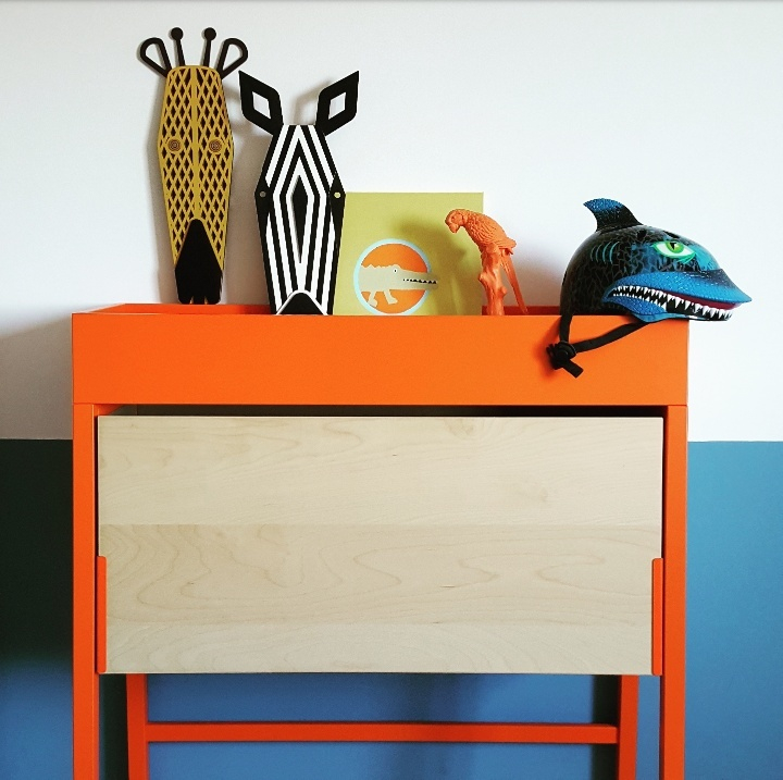 Dekorative Zebra Mini Tiermaske als Wandschmuck auf einem orangefarbenen Regal, einzigartiges Deko-Element für Kinderzimmer.