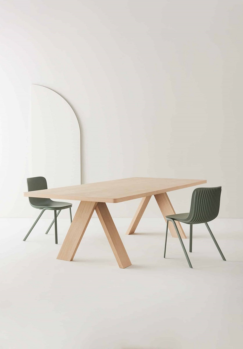Artful Wood Table: Heller Holztisch von Segis mit zwei grünen Stühlen im minimalistischen Design.