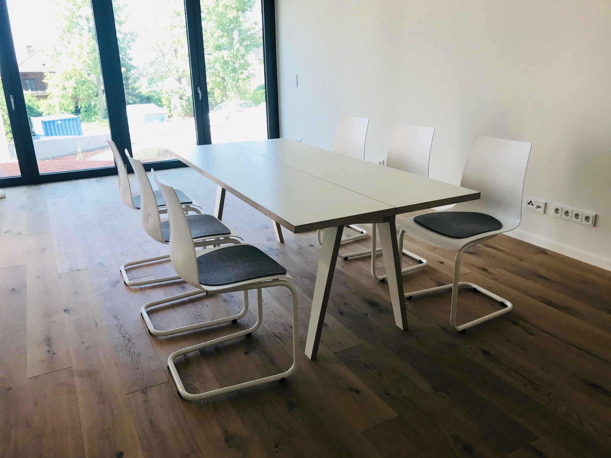 Heller Tojo Tisch mit weißen Stühlen in modernem Esszimmer, minimalistisches Design für Wohnraum.