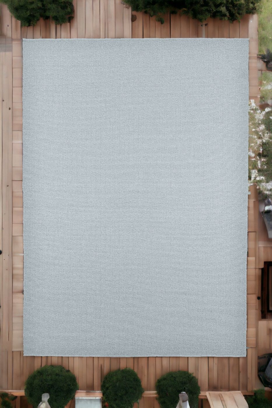 Grauer Koi Outdoor Teppich auf einer Holzterrasse, ideal für Garten und Balkon.