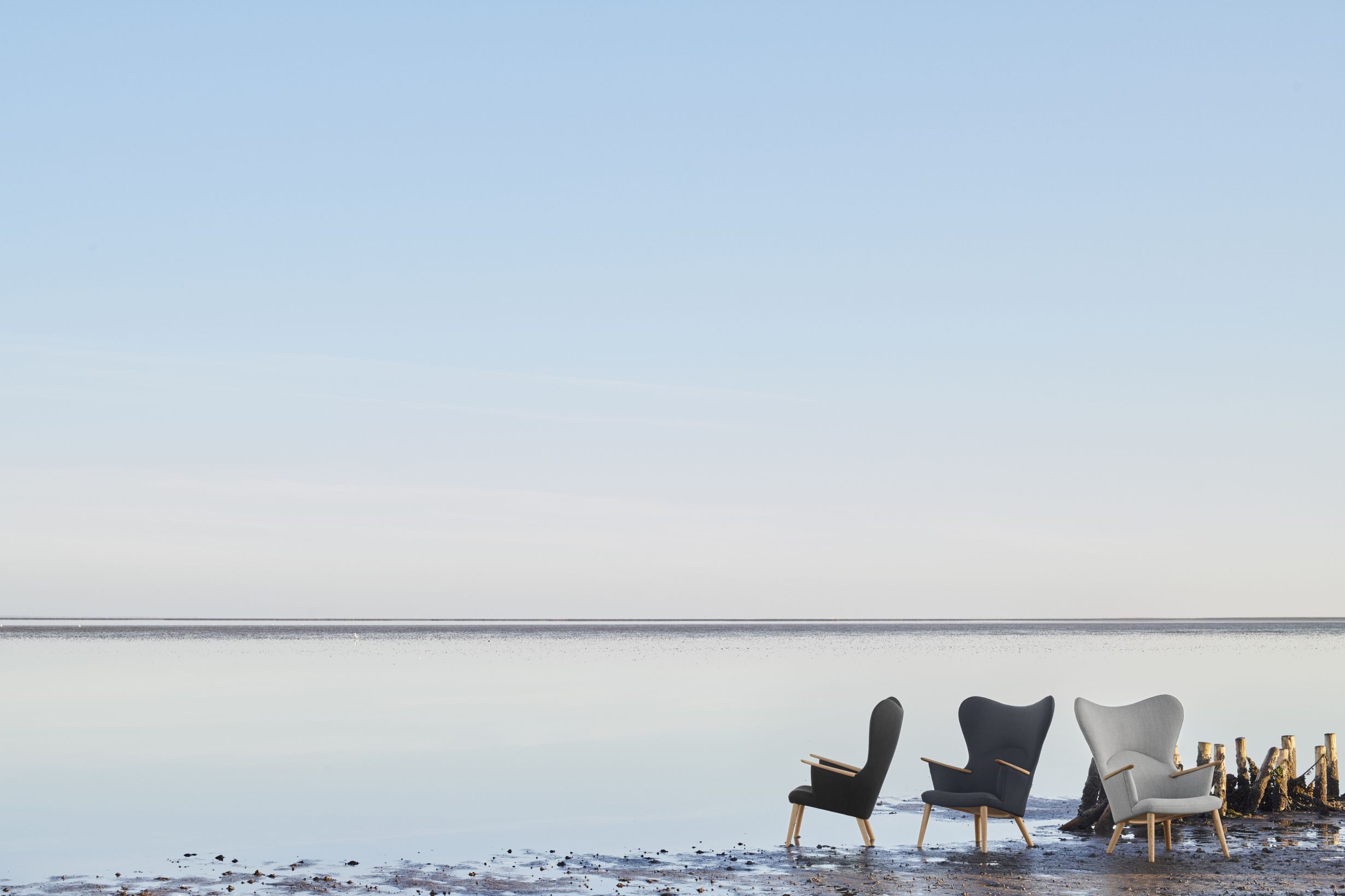 Drei CH78 Mama Bear Sessel von Carl Hansen & Søn am Strand, moderne Loungemöbel.