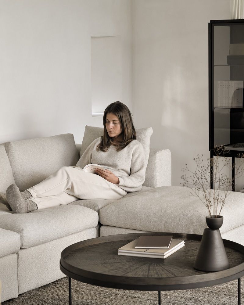Frau liest auf einem Mellow Sofa mit Rückenkissen aus Off White Eco Stoff.