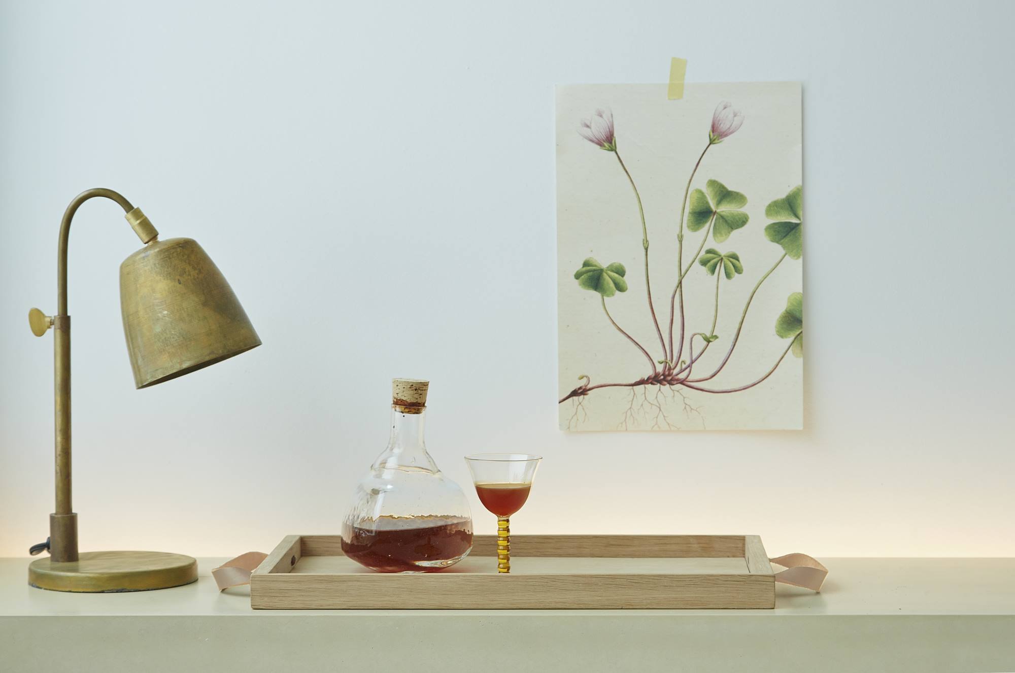 Norr Tray Tablett von Skagerak: Holztablett mit Flasche, Glas und Lampe auf Tisch.