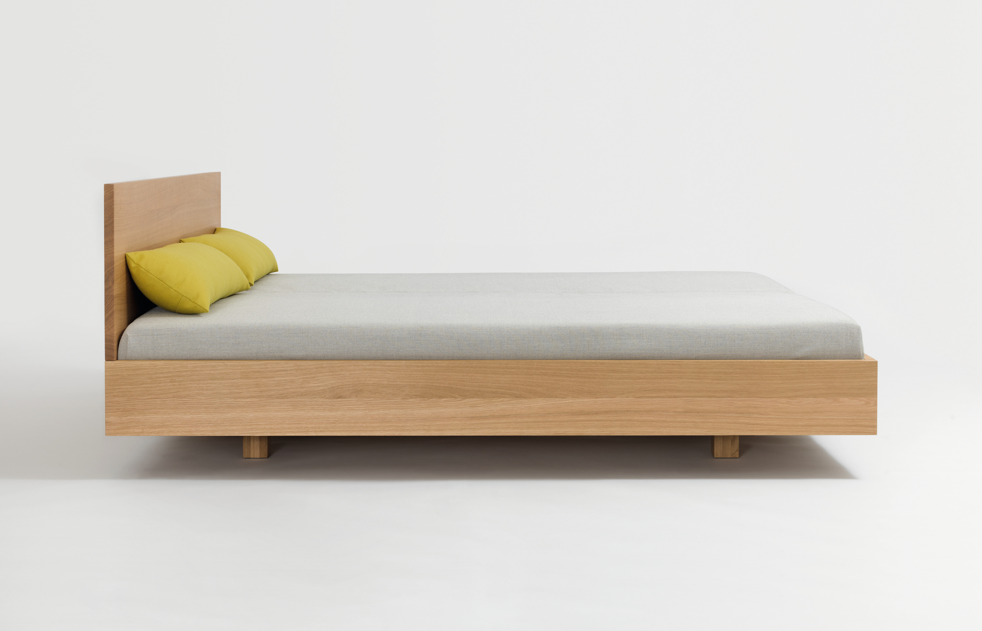 Simple HI Holzbett mit gelben Kissen: Modernes Bettgestell aus hellem Holz für Schlafzimmer.