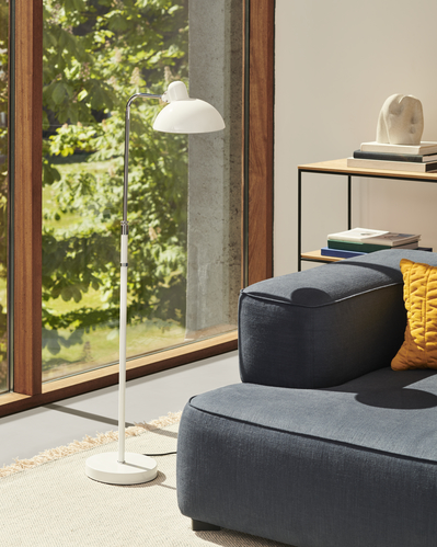 Wohnzimmer mit Fritz Hansen Regal, Stehlampe und blauem Sofa. Modernes Wohnen.