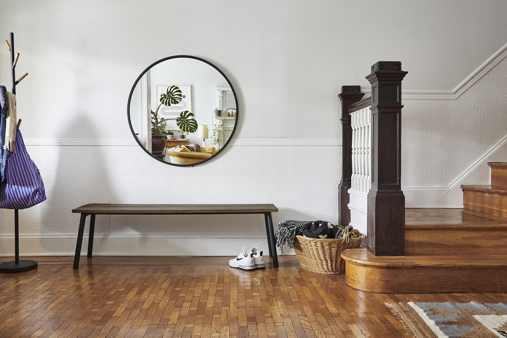 Emeco Run Bench: Holzbank mit schwarzem Gestell im Flur vor Spiegel und Treppe.