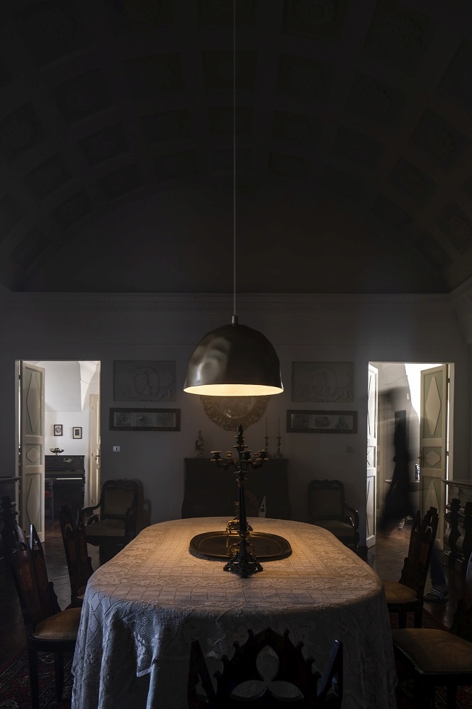 Goldene Bump Pendelleuchte von Foscarini über Esstisch in dunklem Raum, atmosphärische Innenbeleuchtung.