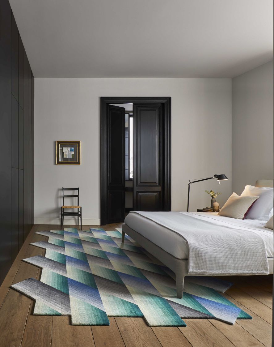 Blauer Mirage Teppich von Gan im Schlafzimmer mit geometrischem Muster und modernem Design.