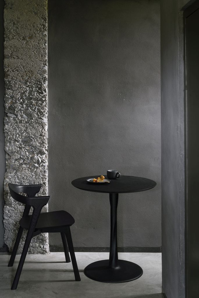 Schwarzer Ethnicraft Torsion Eiche Tisch mit Stuhl und Speisen in minimalistischem Interieur.