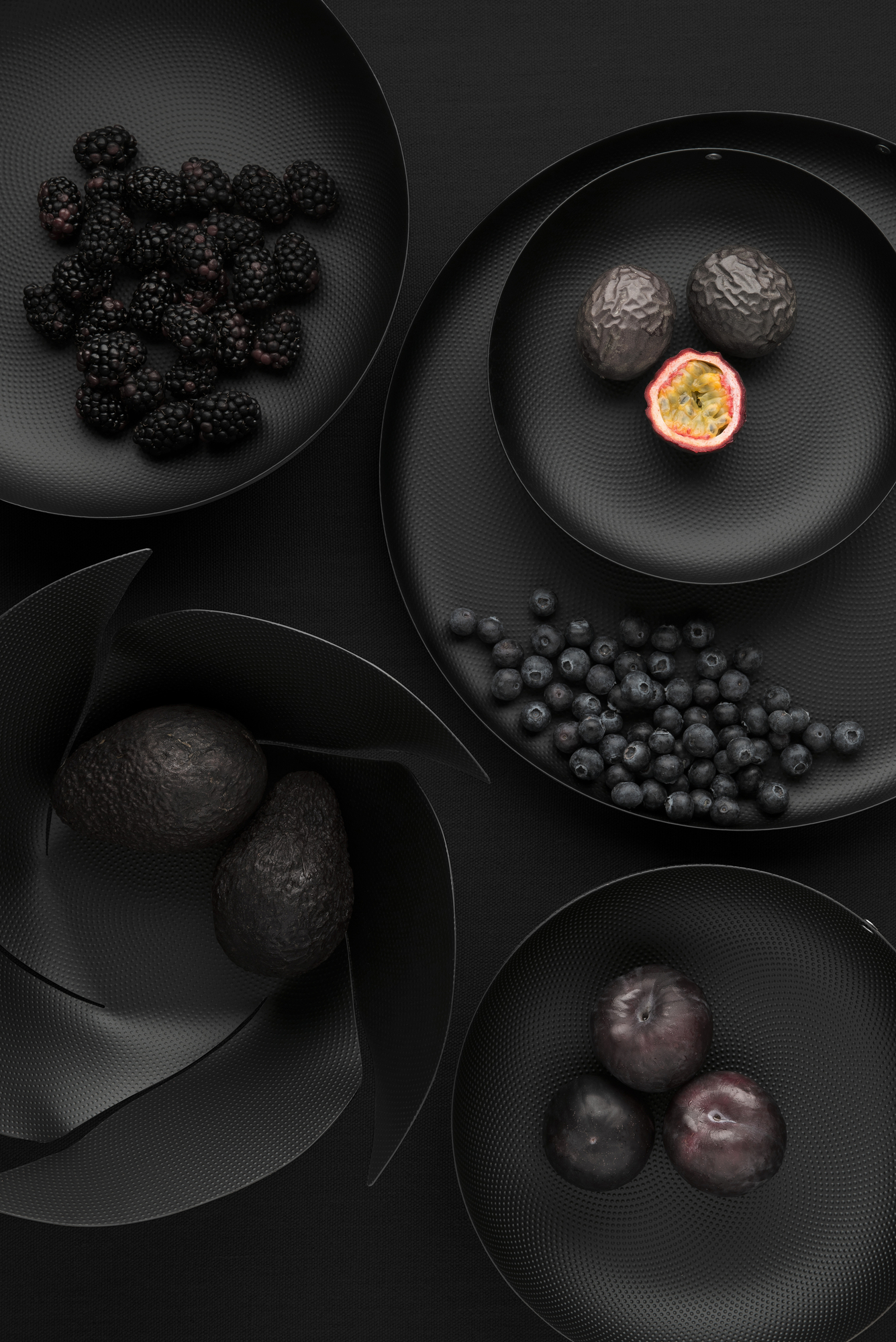 Schwarze Alessi Obstschale JM17/29 mit Avocados, Blaubeeren, Brombeeren, Maracuja und Pflaumen. Runde Design-Schale.