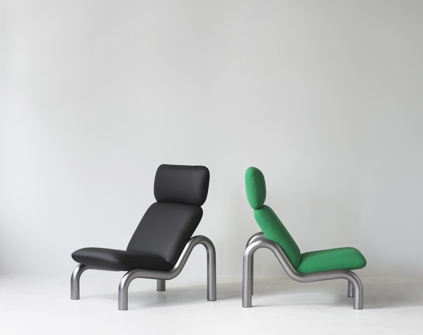 Normann Copenhagen Tube Lounge Chair Sessel in Schwarz und Grün mit Stahlgestell vor weißem Hintergrund.