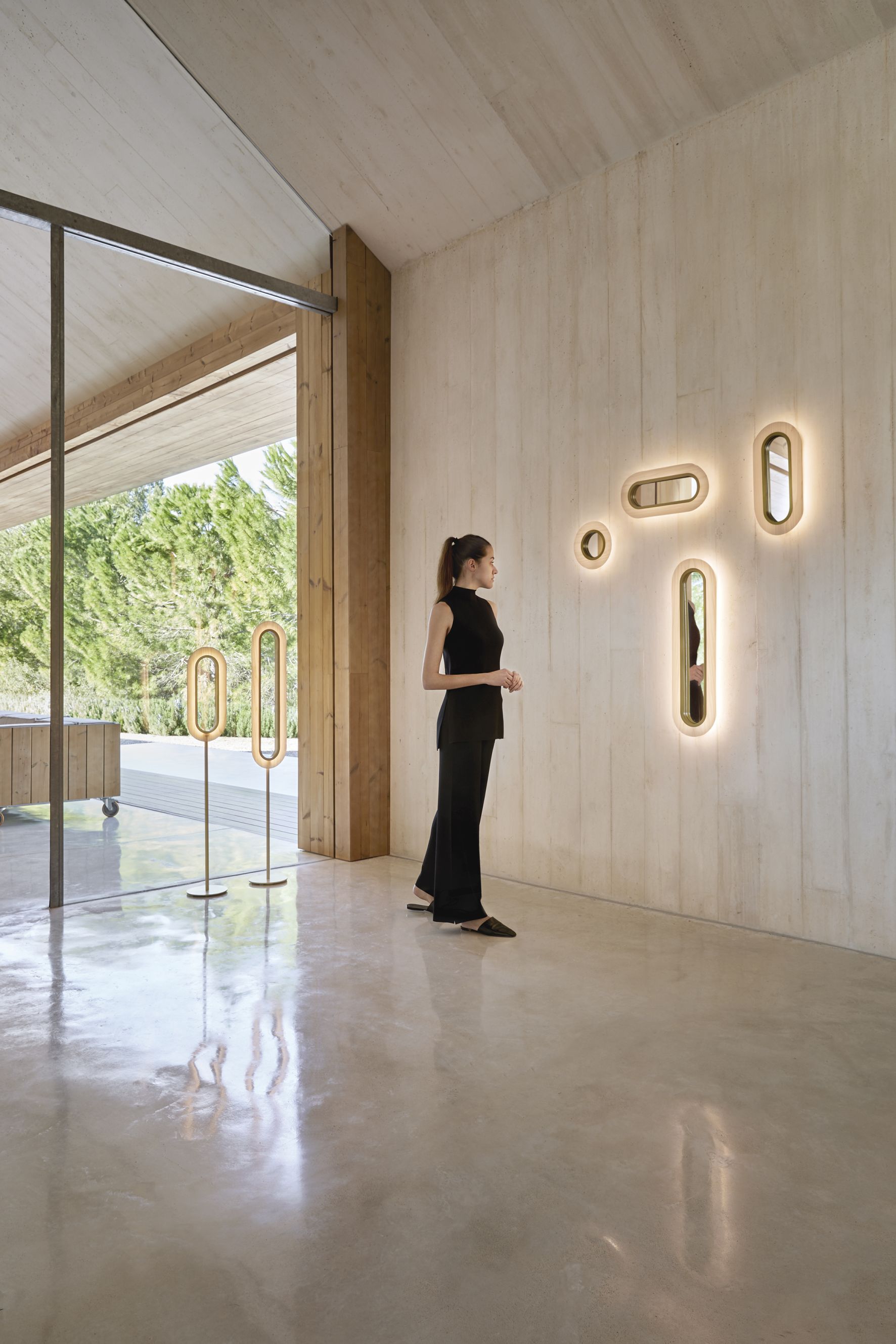 LZF Lamps Lens LED Wandleuchten in Gold und Hellrosa an einer Betonwand.