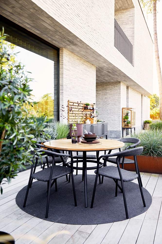 Runder Joy Outdoor Esstisch von Cane-Line aus Teakholz mit taupefarbenem Gestell und Stühlen.